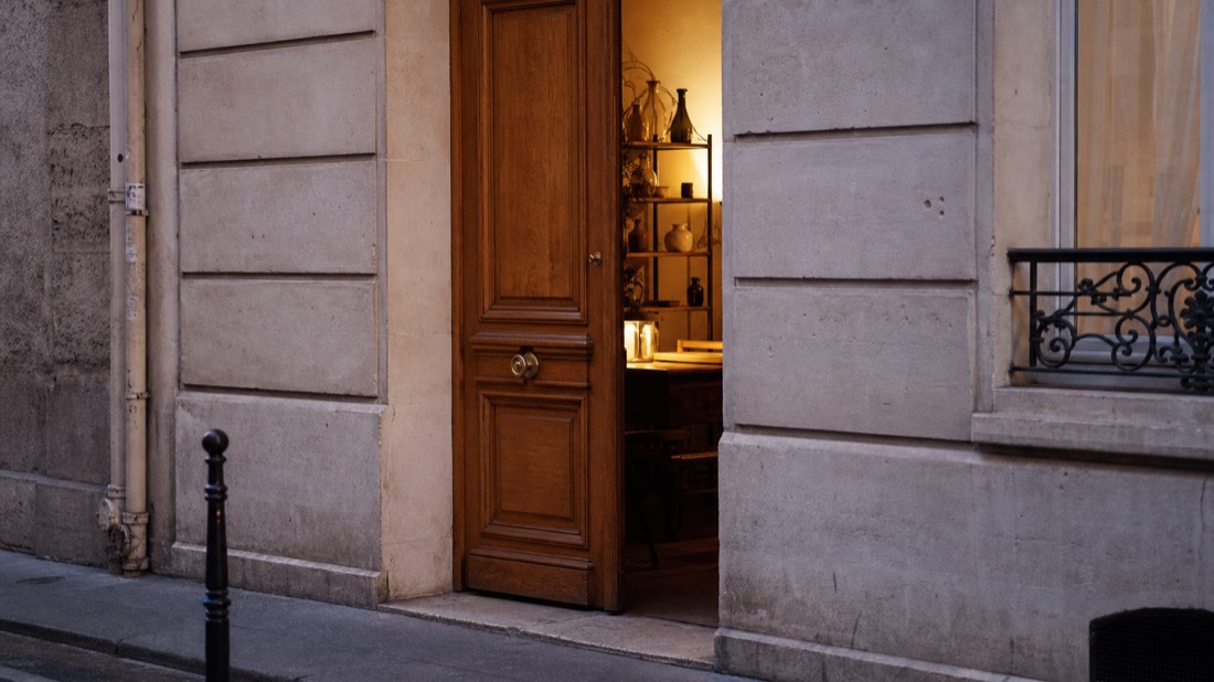 Doorway of a quiet Paris atelier seen from the street with warm light inside and no signage