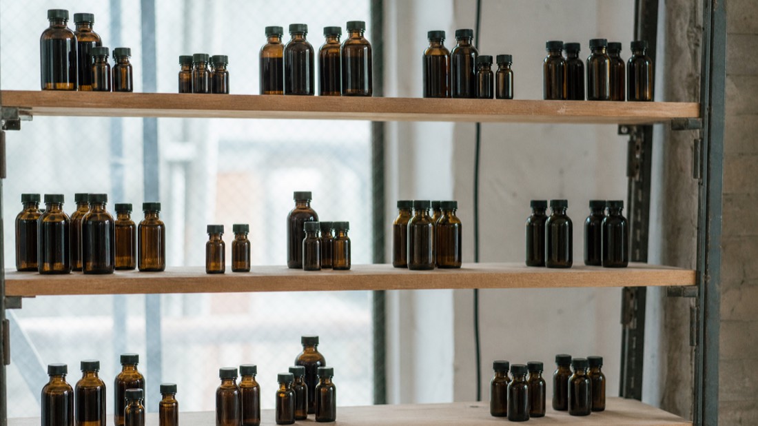 Clusters of small amber bottles grouped in sections along a tiered workshop rack, arranged by fragrance family