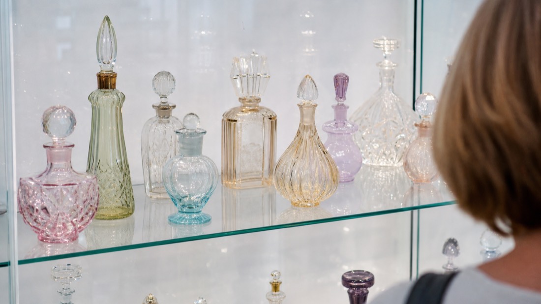 Ornate vintage perfume bottles displayed behind glass in a Paris perfume museum vitrine