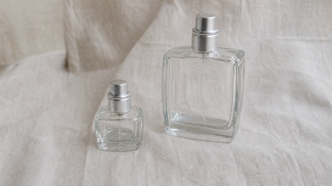 Small perfume flacon beside a larger one on pale linen, choosing between a short and a long Paris workshop