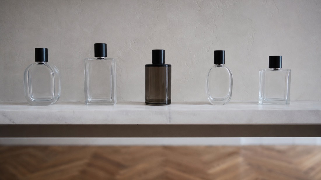 Row of different-sized unbranded perfume bottles on a marble shelf, comparing perfume workshop prices in Paris