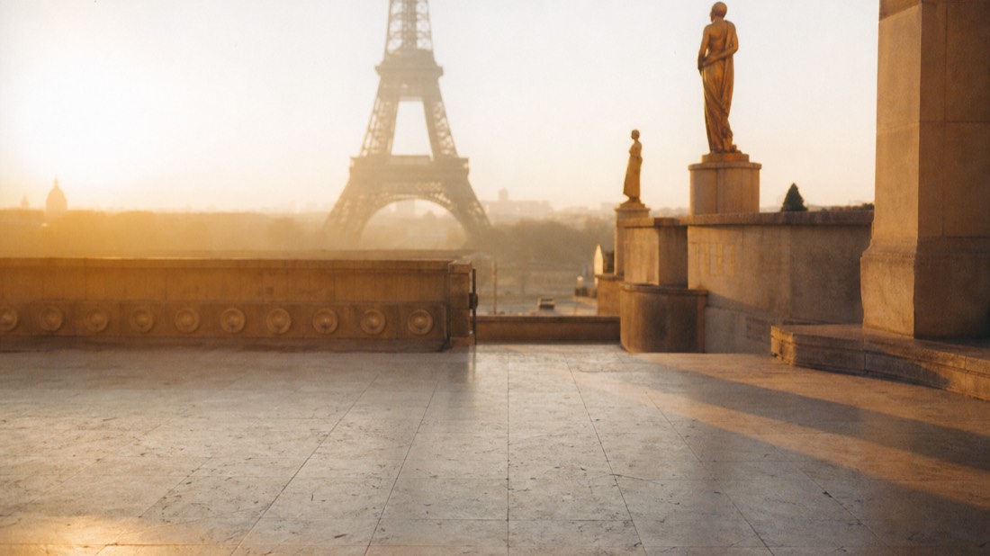 Golden evening light over the Trocadero esplanade stonework with the Eiffel Tower softly blurred across the river
