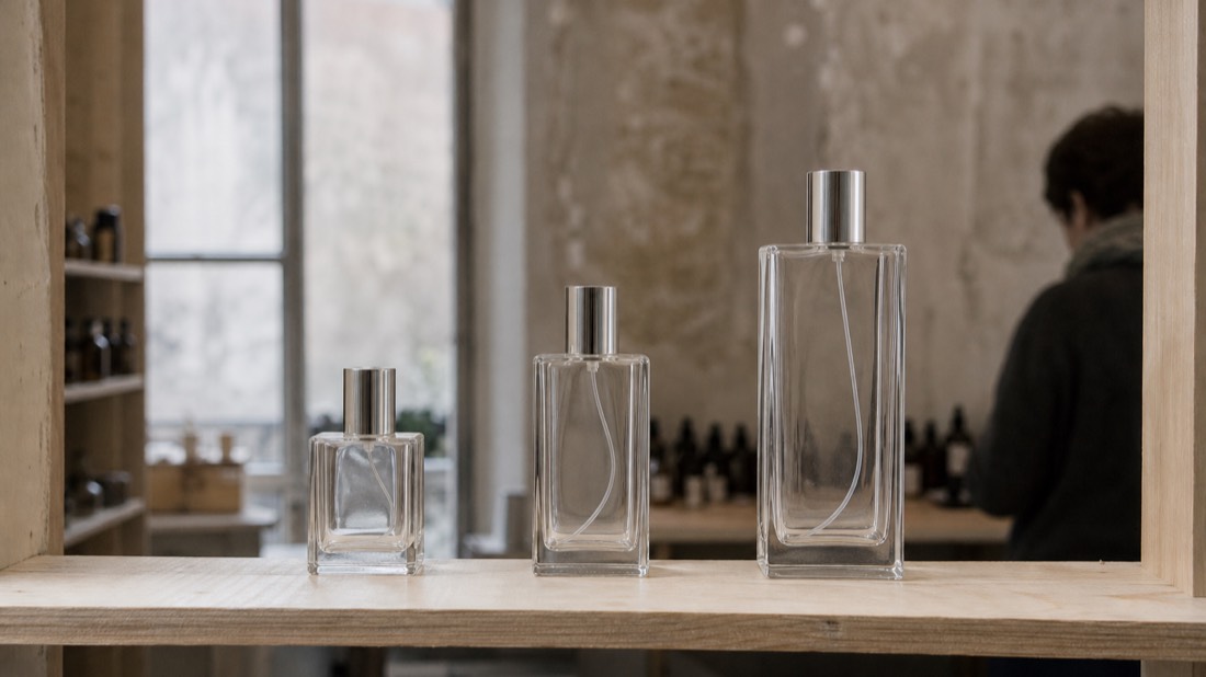 Three unbranded perfume bottles of increasing size lined up on a Paris workshop shelf, from child to teen to adult session
