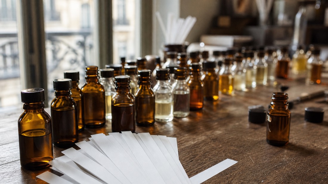 Scent strips fanned out beside labeled-free essence vials on a workbench, matching Paris workshop options to different ages